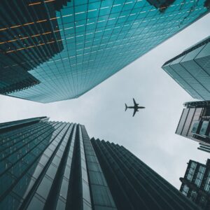 Самолет лети над високи небостъргачи в модерен град