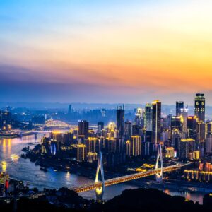 Панорамна снимка на град при залез със светещ мост и небостъргачи