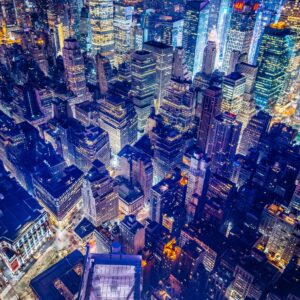 Нощна въздушна снимка на Ню Йорк с осветени улици и небостъргачи