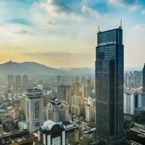 Градски изглед към китайски мегаполис по изгрев с небостъргачи и планини.