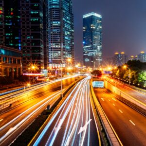 Нощен град с трафик и осветени небостъргачи