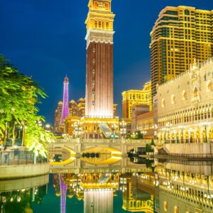 Нощна гледка на Макао с осветена кула и отражения във водата
