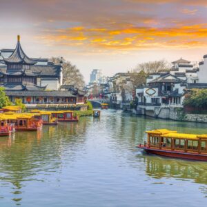 Китайски лодки по река на залез със стари сгради