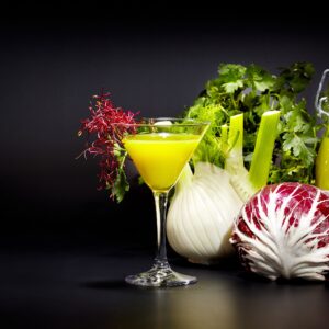 Жълт коктейл със зеленчуци и билки върху тъмен фон