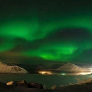 Северно сияние над заснежени планини през нощта.