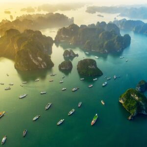 Лодки в Халонг Бей при залез над зелените острови.