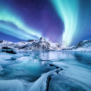 Северно сияние над замръзнало езеро със сняг и планини.