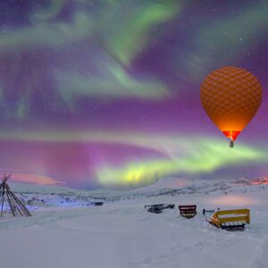 Балон над зимен пейзаж със северно сияние