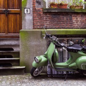 Класическа зелена Vespa пред тухлена къща