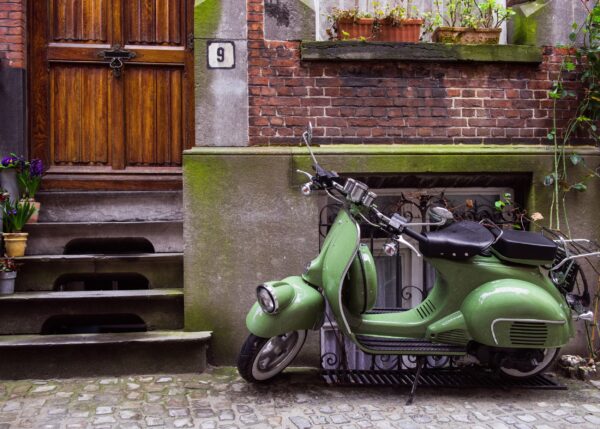 Класическа зелена Vespa пред тухлена къща