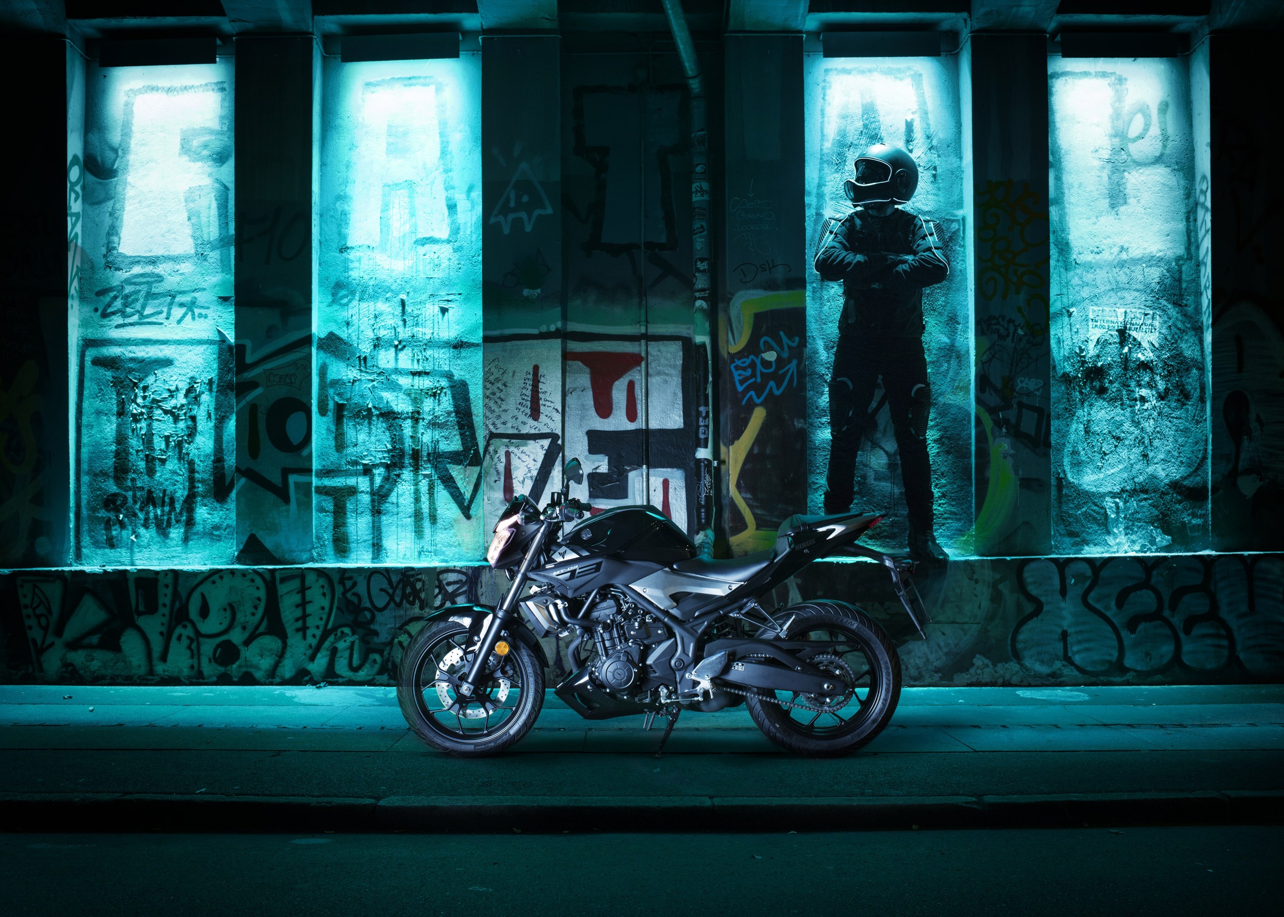 Motorcycle in neon blue light under graffiti wall
