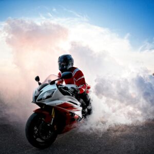 Спортен мотор в червено и бяло с облаци дим на фона на небе