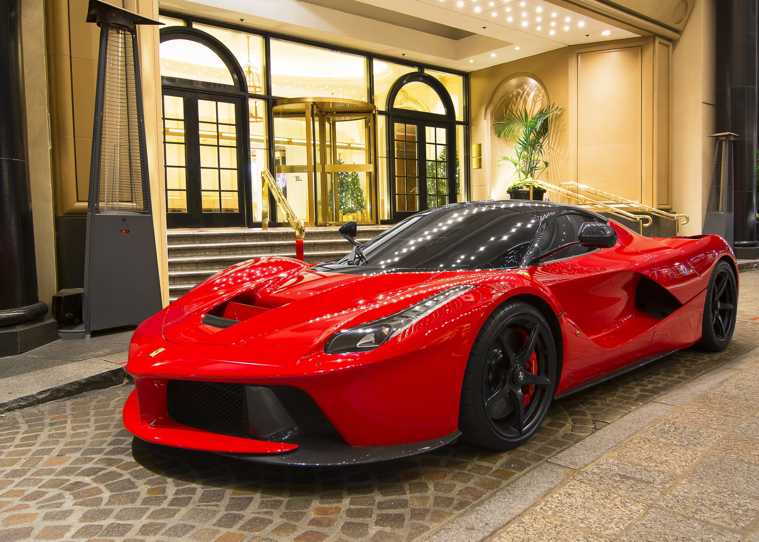 Червена Ferrari LaFerrari пред входа на луксозен хотел