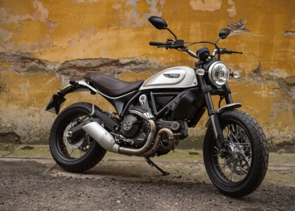 Ducati Scrambler бяло-черен мотор пред жълта стена
