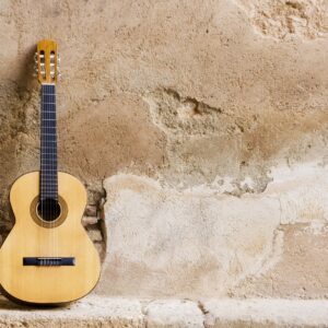 Класическа китара подпряна до стара каменна стена