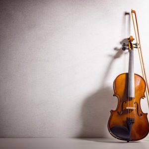 Цигулка с лък пред светла стена