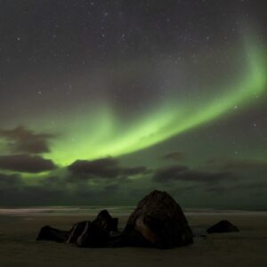 Северно сияние над плаж с камъни в тъмното небе