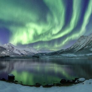 Северно сияние над езеро и планини със зимен пейзаж