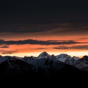 Залез над заснежени планини с драматично небе