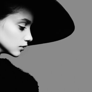 Жена в черно-бяла фотография със стилна шапка.