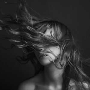 Жена с развята коса в черно-бяла фотография.