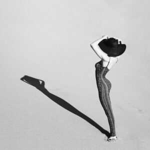 Жена в черно-бяла фотография, заснета в пустинята със сянка.