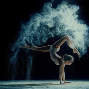 Танцьорка в артистична фотография с облак прах на тъмен фон.
