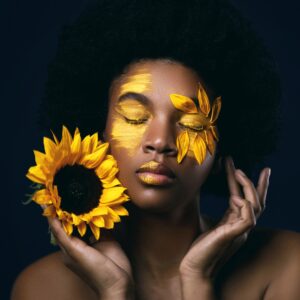 Жена с лице, украсено със слънчогледи и жълта боя.