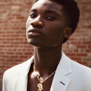 Elegant man in a white suit with gold necklace portrait.