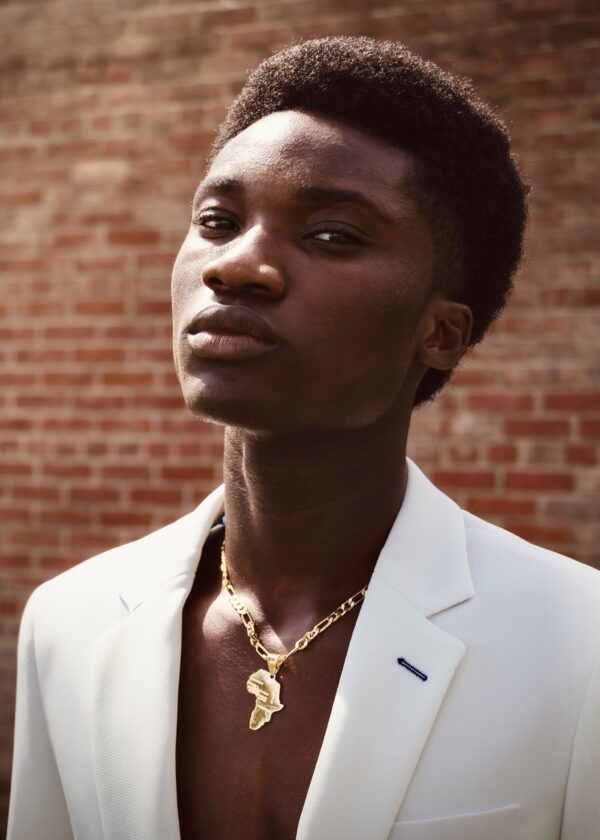 Elegant man in a white suit with gold necklace portrait.