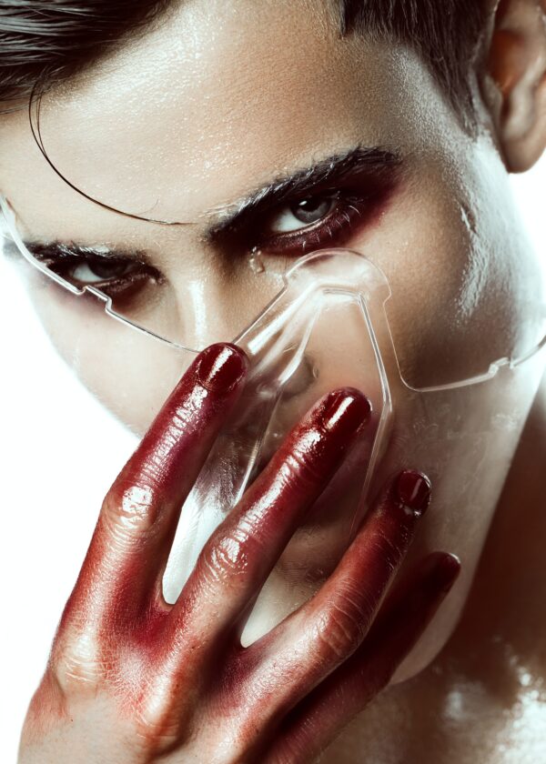 Man with red paint hands and transparent mask.