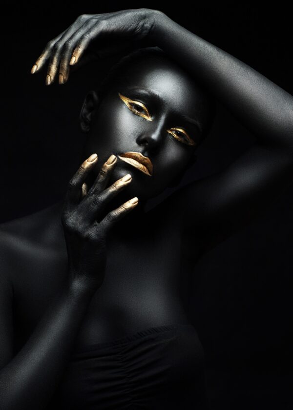 Artistic portrait of a woman with black skin and golden highlights.