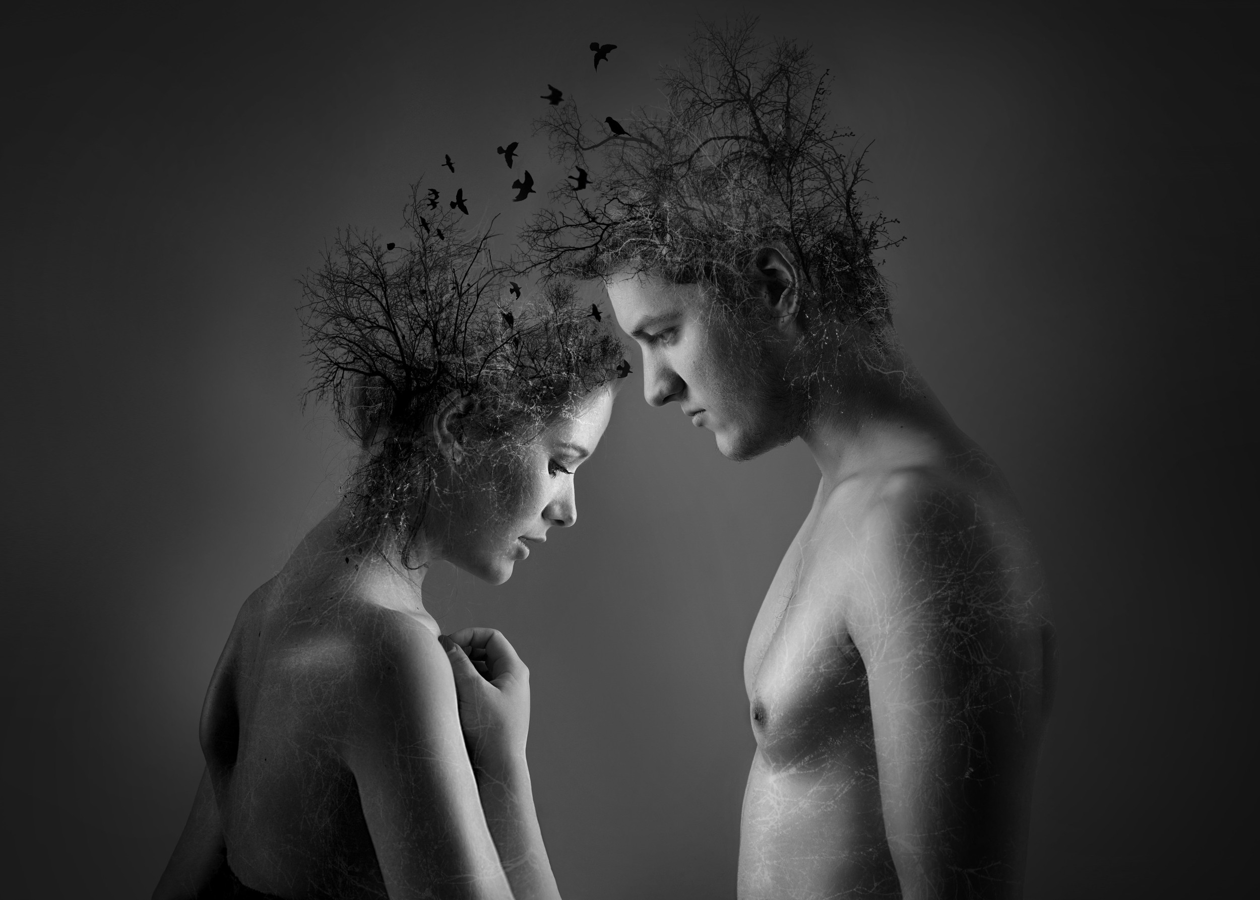 Conceptual black and white portrait of man and woman with nature elements.