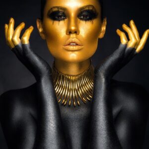 Artistic portrait of a woman with golden face and black body paint.