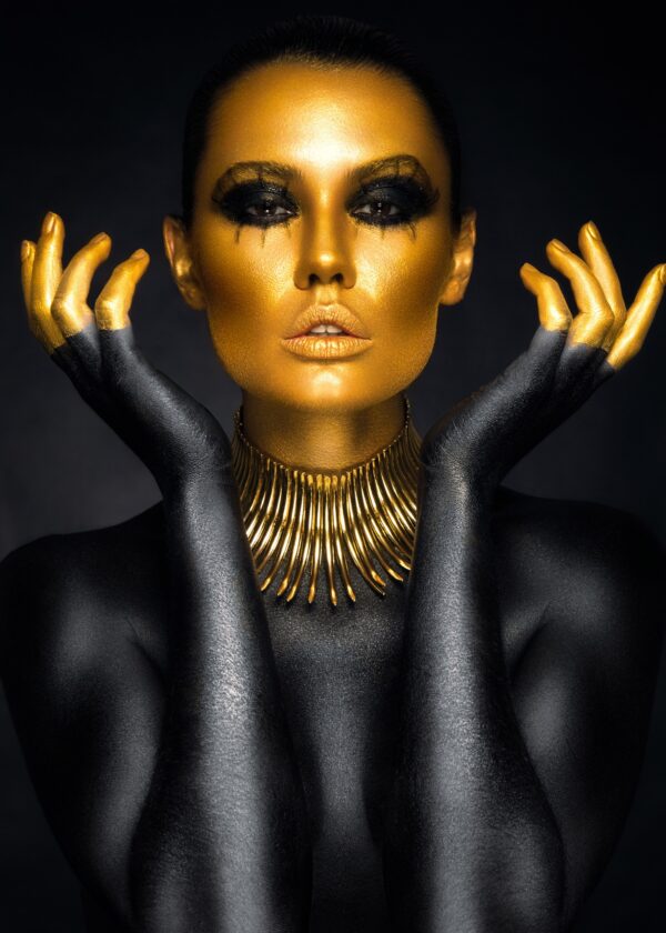 Artistic portrait of a woman with golden face and black body paint.