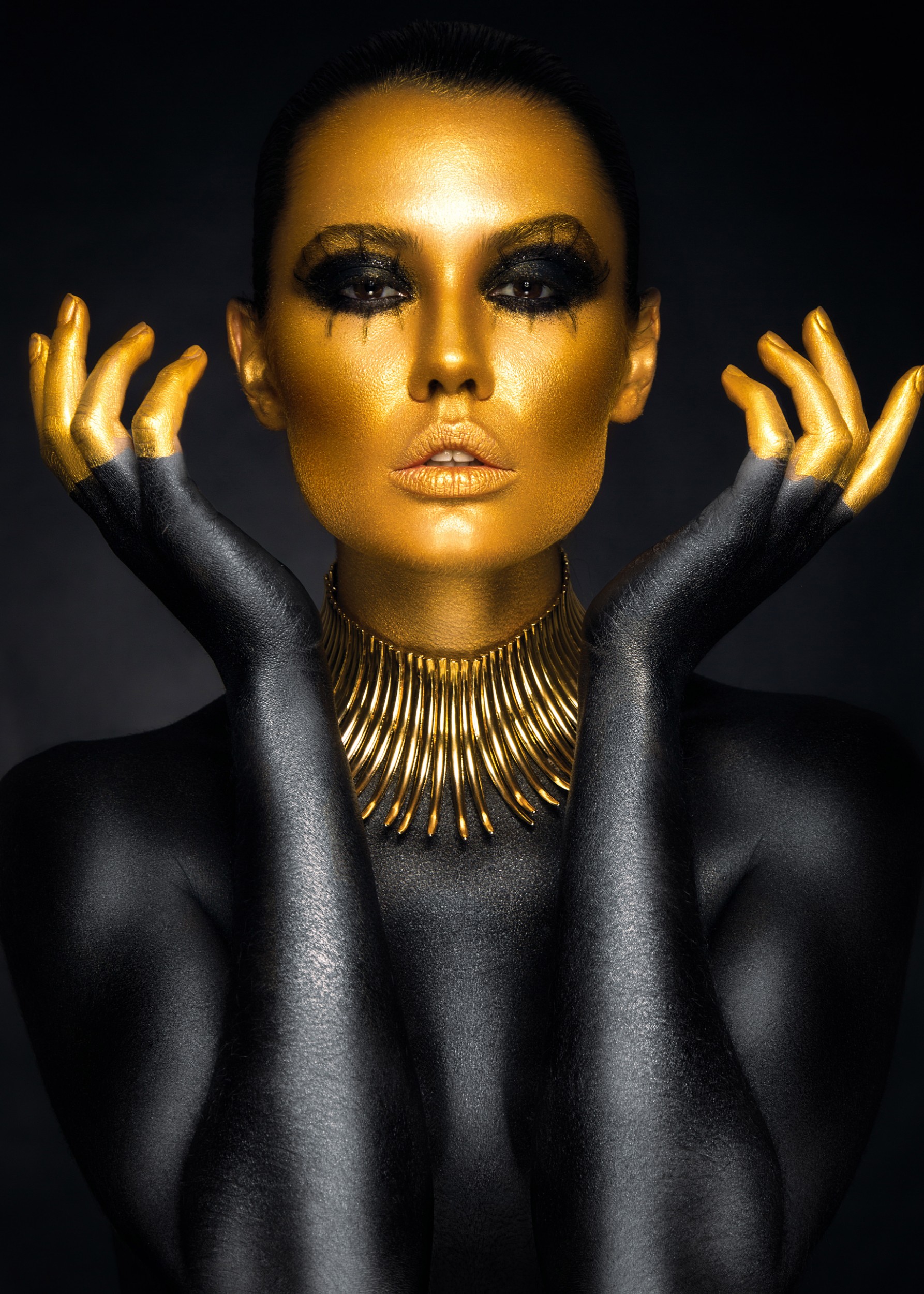 Artistic portrait of a woman with golden face and black body paint.
