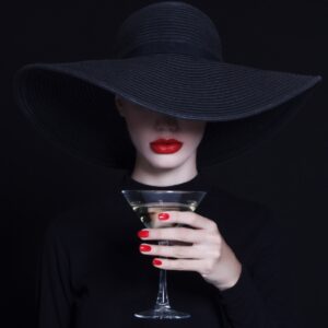 Жена с червени устни и черна шапка държи чаша вино – минималистична фотография.