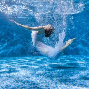 Балерина под вода с бяла рокля – магична фотография.