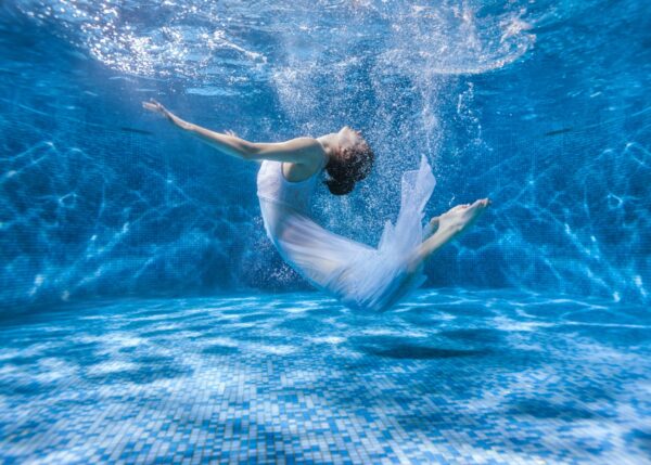 Балерина под вода с бяла рокля – магична фотография.