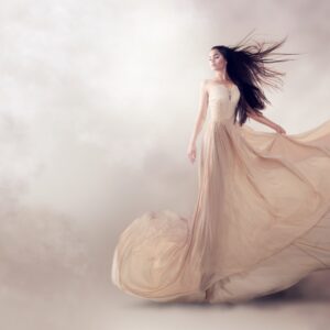 Artistic photo of a woman in a flowing beige dress among clouds.