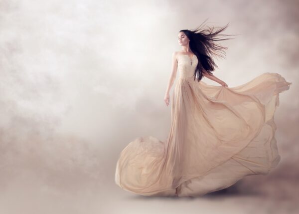 Artistic photo of a woman in a flowing beige dress among clouds.