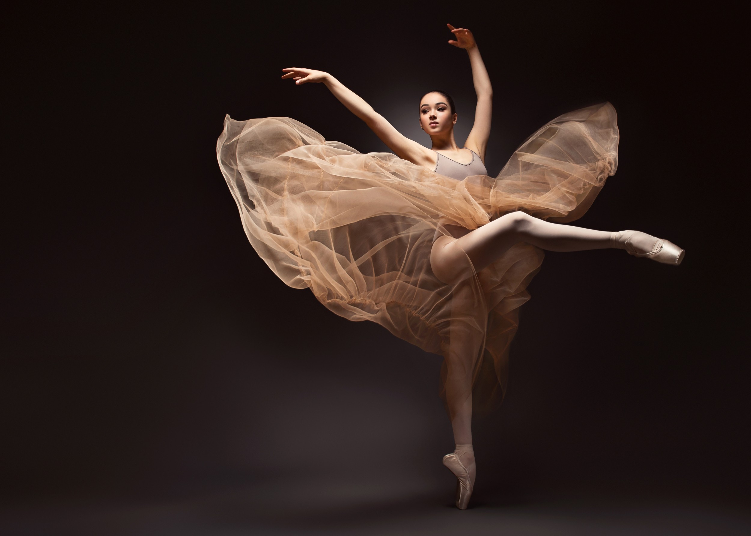 Балерина в елегантна поза с бежова пола