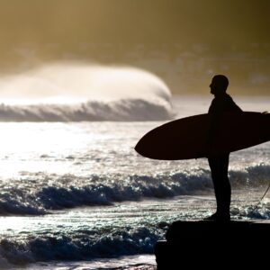 Силует на сърфист при изгрев на морския бряг.